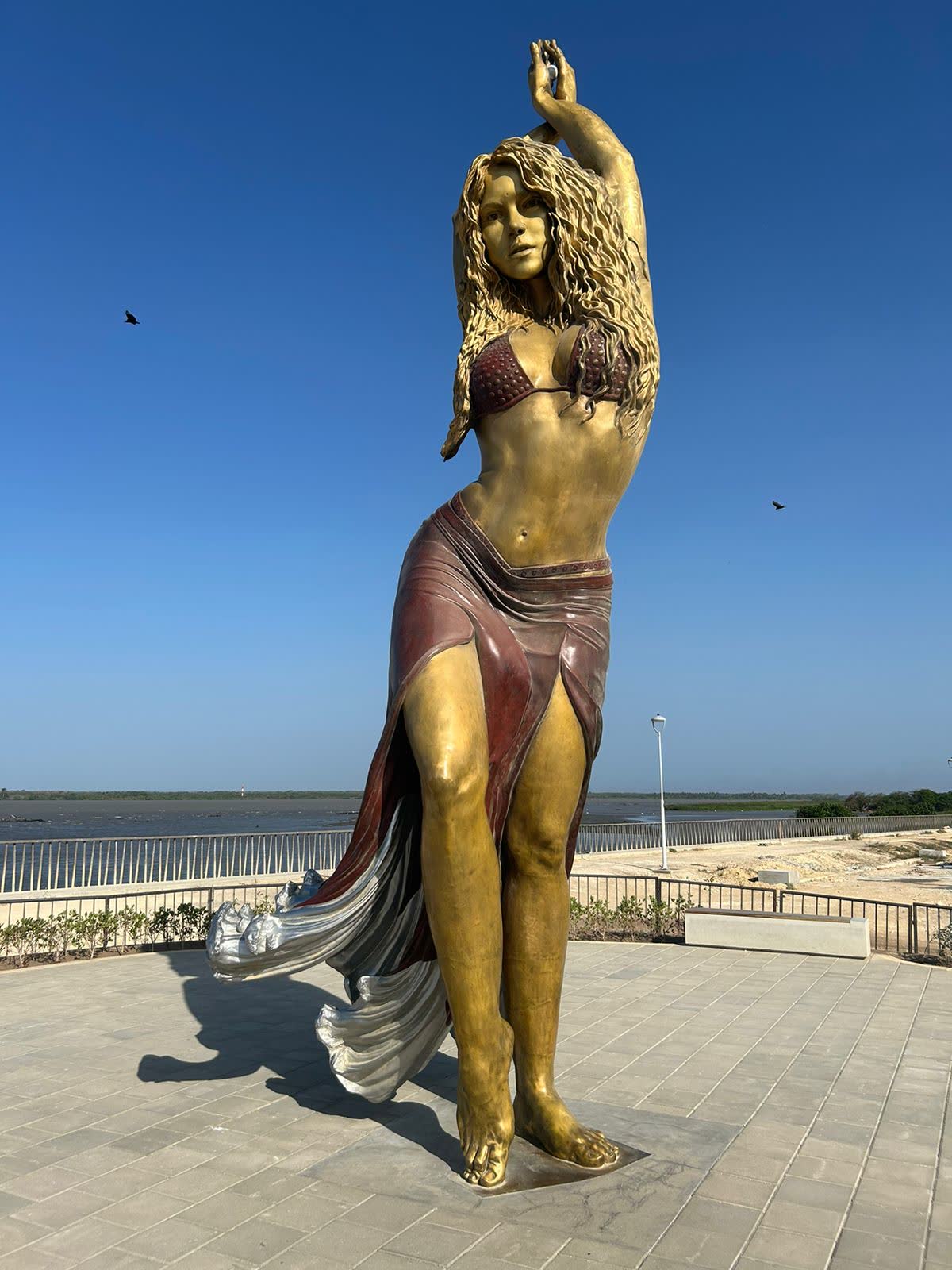 Estatua de bronce de Shakira bailando, con una falda que termina en forma de olas, en el malecón de Barranquilla
